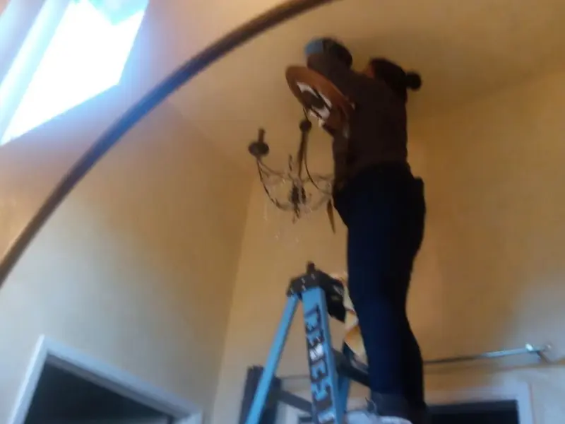 Electrician installing a chandelier in a Archbald residence